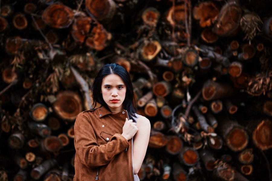 a creative personal branding portrait of a music artist taken against cut logs as a backdrop